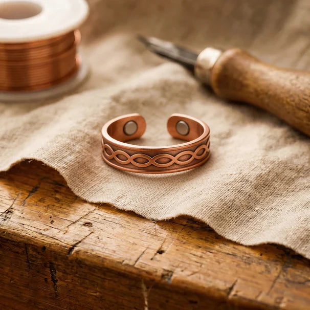 Adjustable copper ring with hand-cut woven pattern displayed on natural linen fabric with crafting tools
