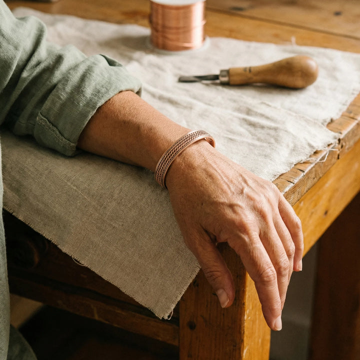 Close-up of women's copper cuff bracelet showing detailed woven rope texture and open adjustable design