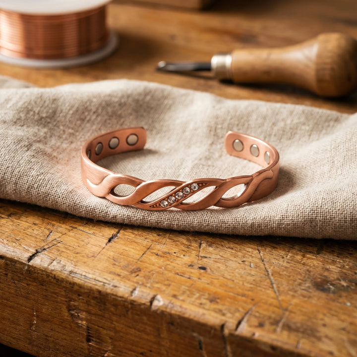 Copper cuff bracelet with twisted design and crystal accents on linen fabric
