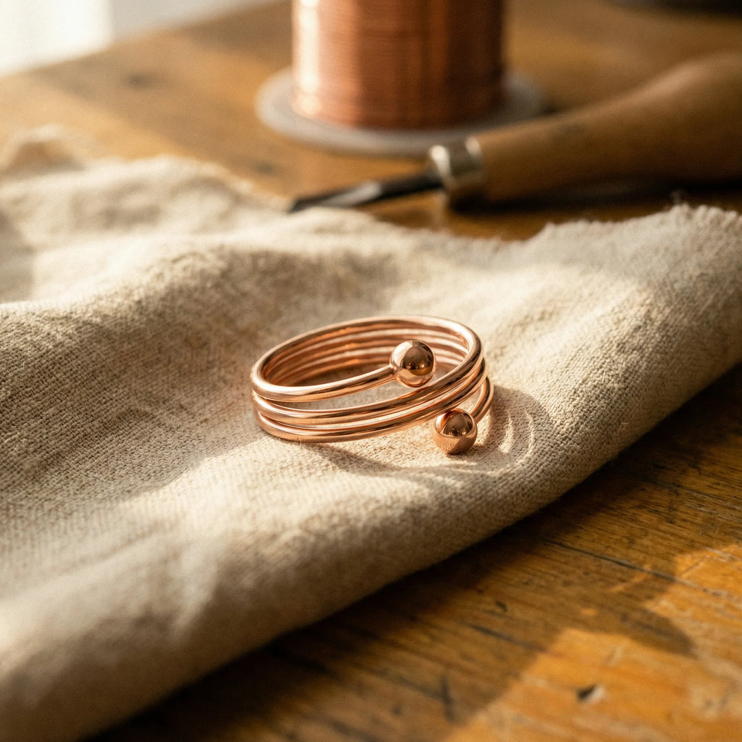 Women's copper spiral ring with three-band coil design resting on linen fabric