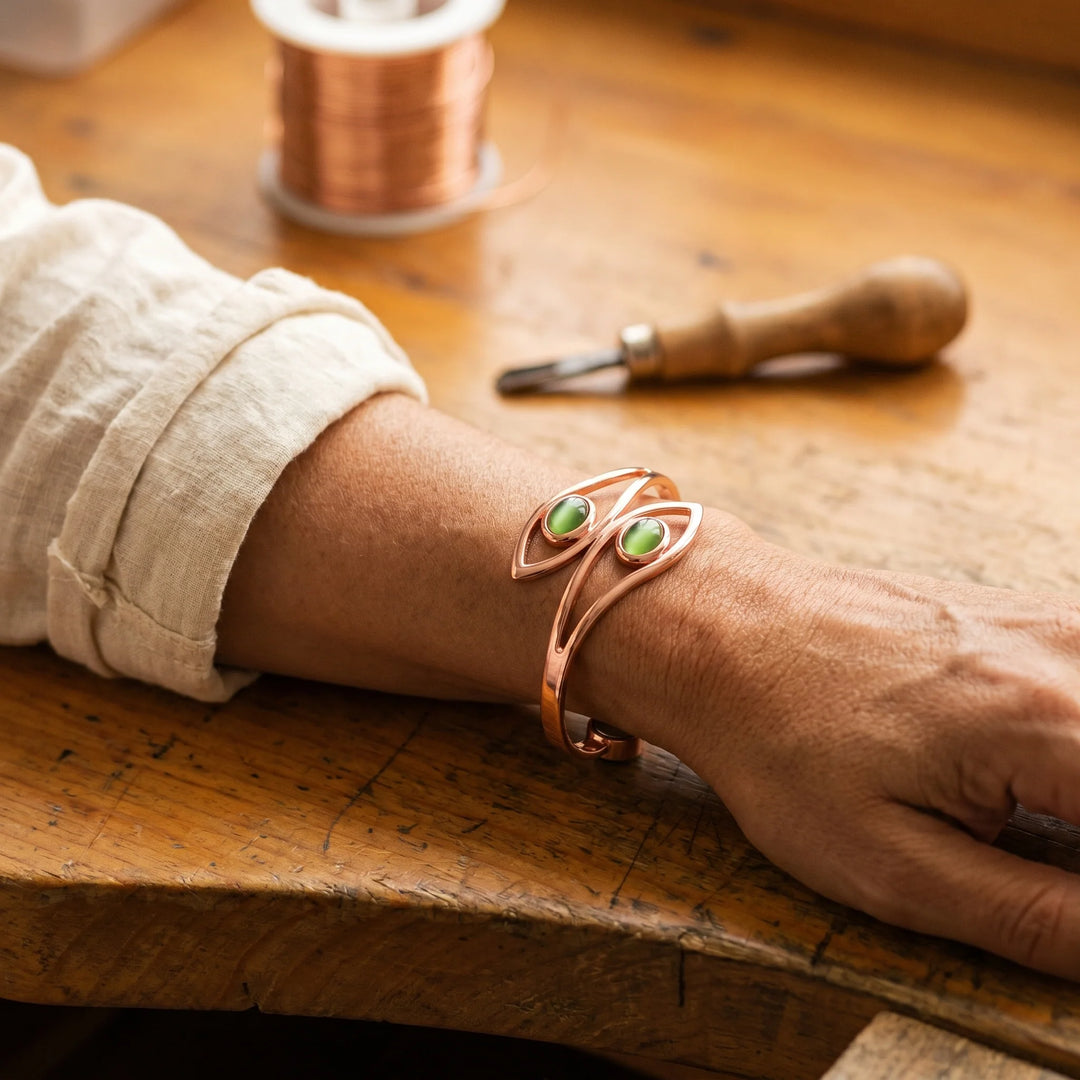 Close-up view of copper cuff bracelet showing sculptural wire design and green stones