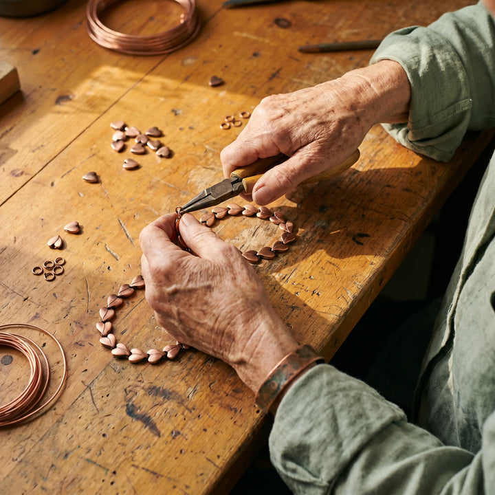 Artisan copper necklace with continuous braided links sitting at collarbone level in natural daylight
