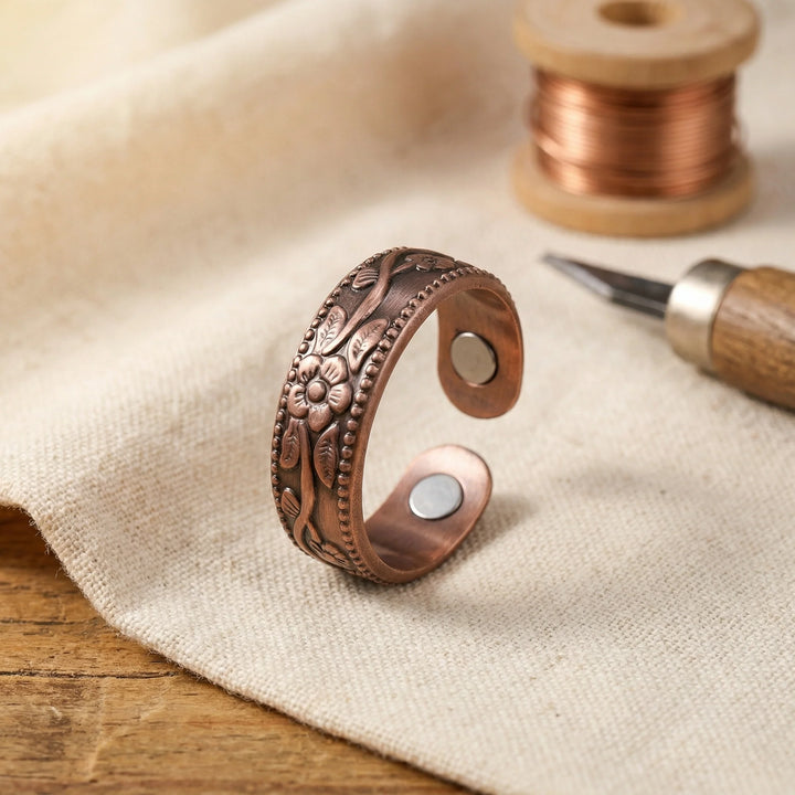 Copper floral adjustable ring with hand-detailed petal motif and beaded border on linen fabric