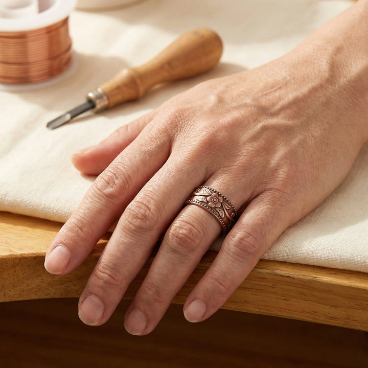 Close-up view of copper ring showing raised floral relief and magnetic interior elements