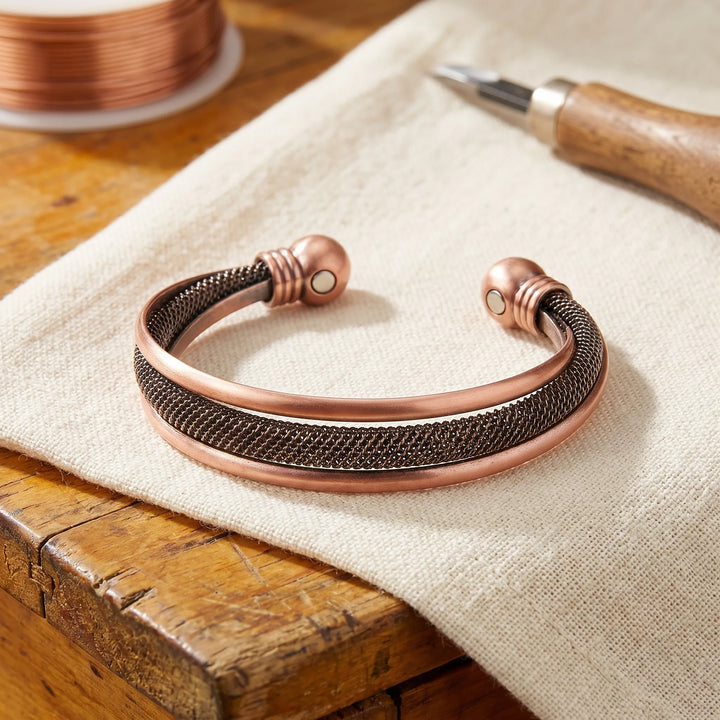 Copper mesh cuff bracelet with hand-tensioned detail and ball-end terminals displayed on linen cloth
