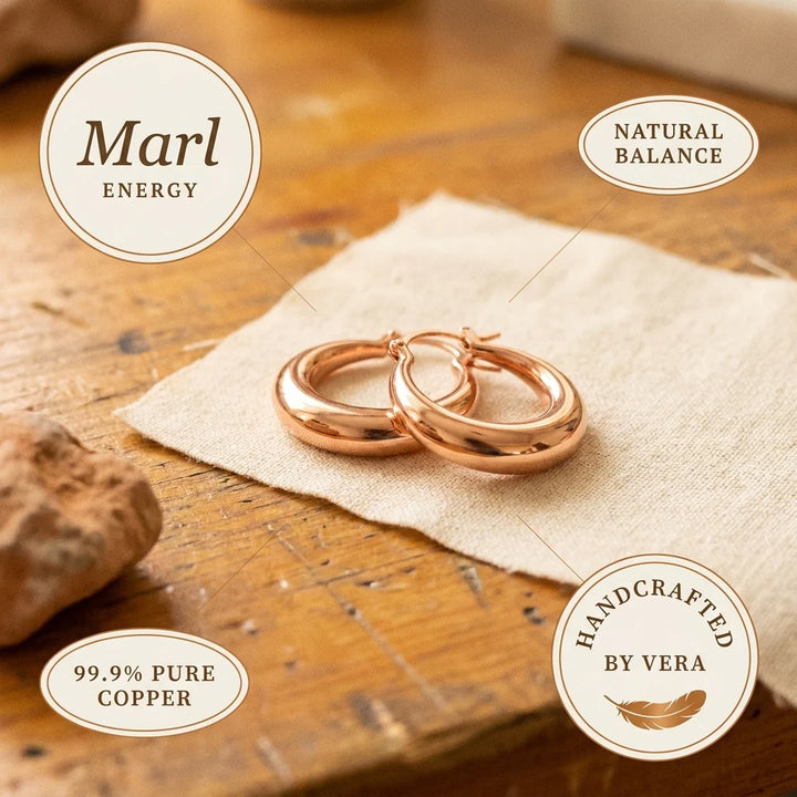 Rose gold hoop earrings on textured fabric showing secure hinge closure and tapered design