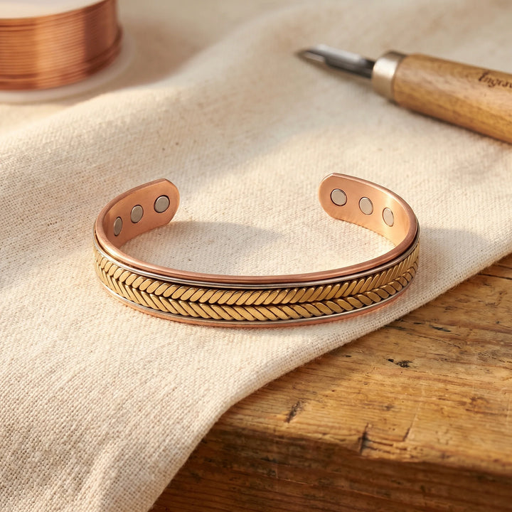 Copper cuff bracelet with hand-pressed chevron pattern and open adjustable design on linen surface