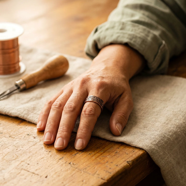 Adjustable copper cuff ring with hand-engraved details and magnetic points on textured fabric
