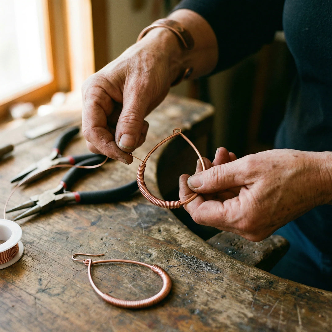 Handcrafted copper hoop earrings with wire wrapping along lower half resting on natural fabric