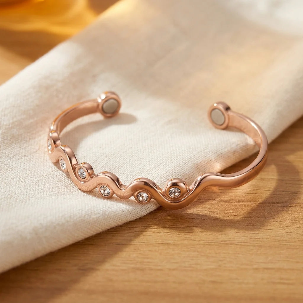 Women's copper cuff bracelet with wave design and crystal accents on wooden surface
