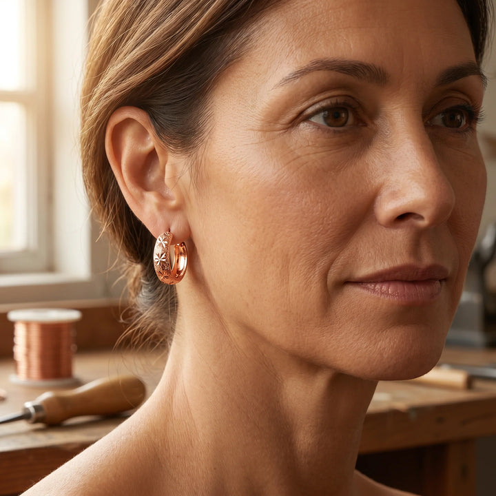 Close-up of star engraved hoop earrings showing textured surface and hinged closure detail