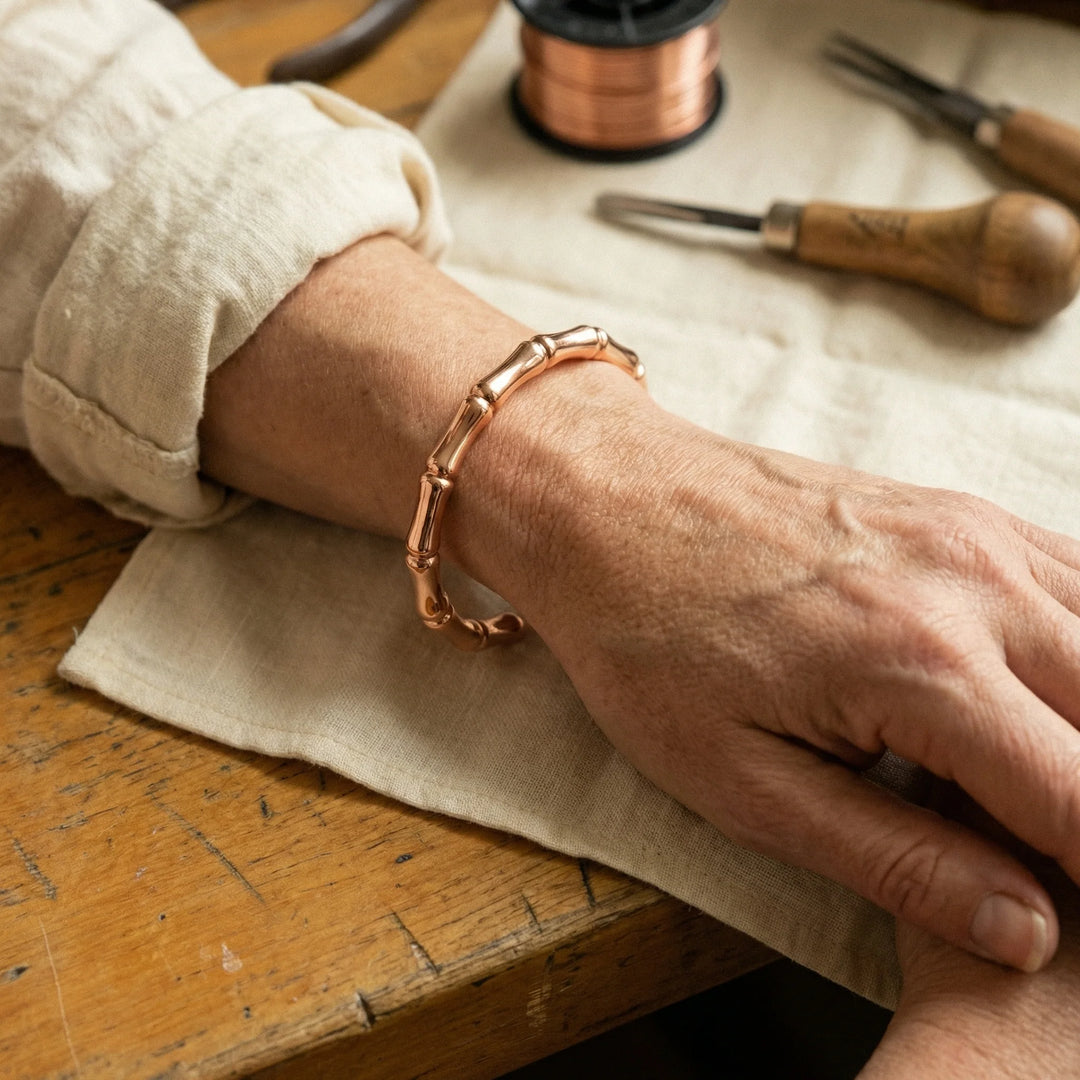 Close-up of copper bamboo bracelet showing polished rose gold finish and sculptural segments