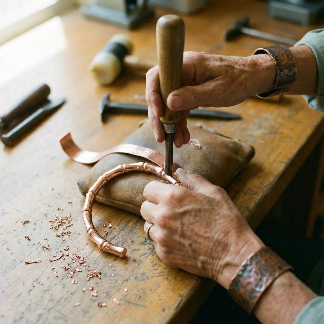 Hand-formed copper bracelet with rounded bamboo nodes displayed on natural linen textile