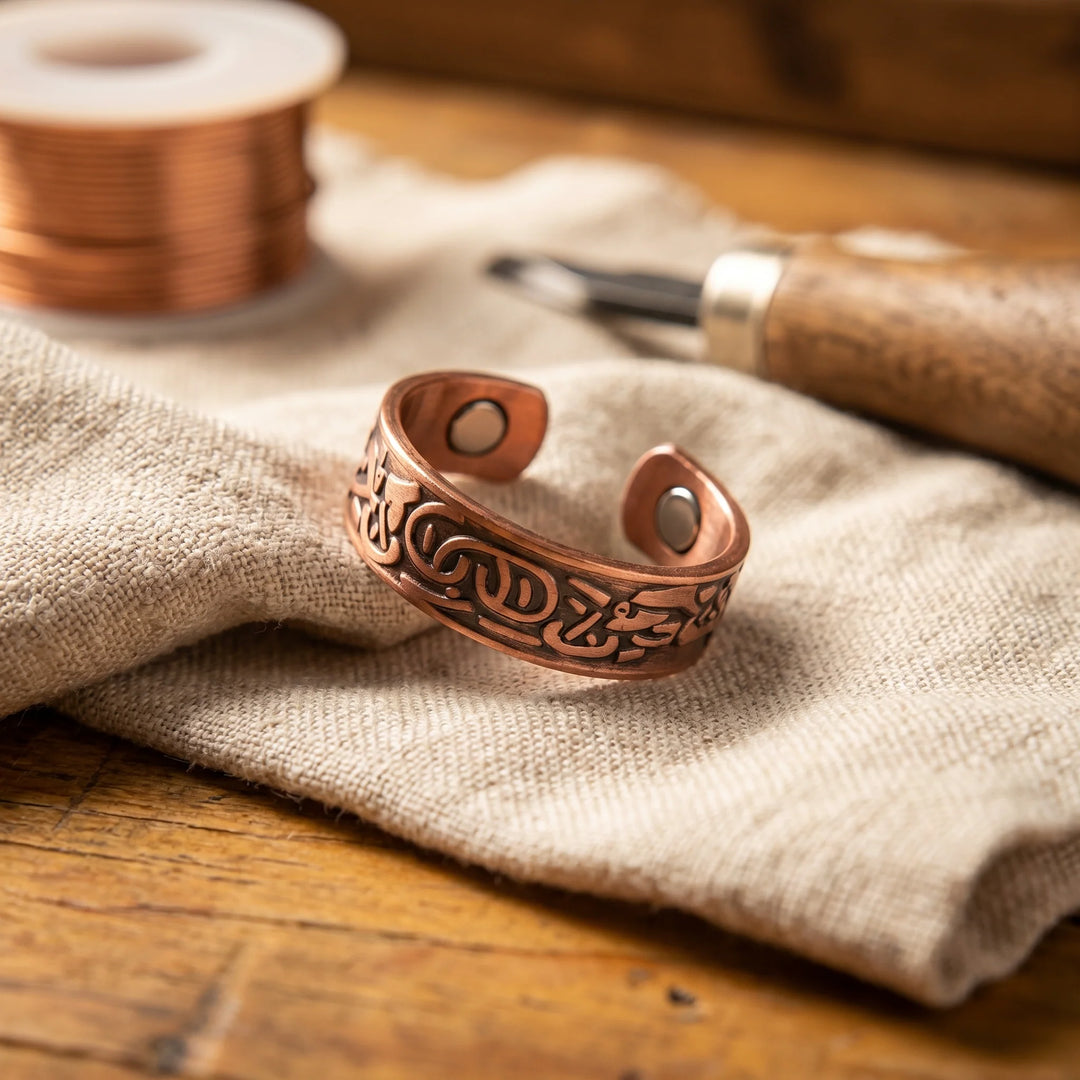 Women's adjustable copper ring with engraved scrollwork and magnetic inlay resting on linen fabric