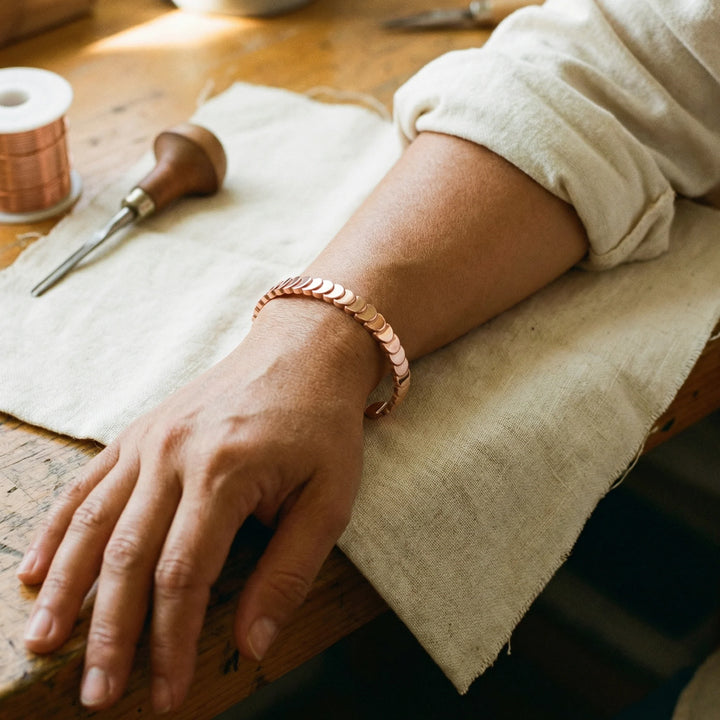 Close-up of adjustable copper cuff bracelet showing textured scale pattern and brushed metal finish