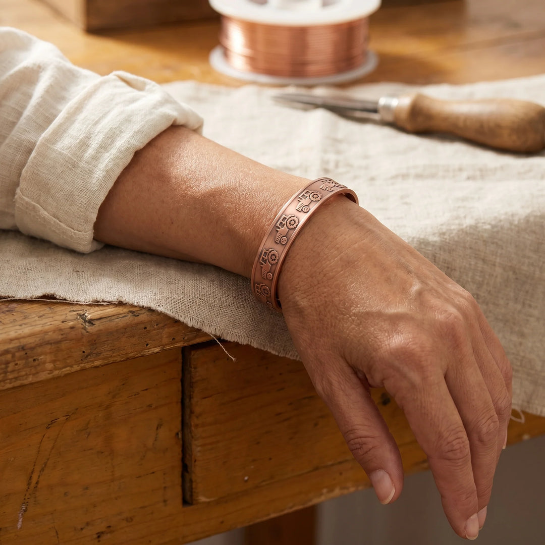 Close-up view of copper cuff bracelet showing detailed tractor embossing and smooth finish