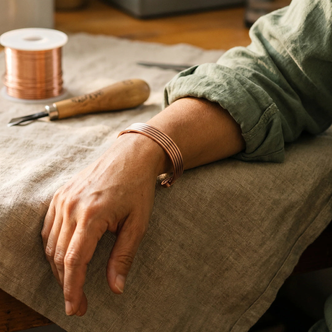 Close view of adjustable copper cuff bracelet showing parallel ridged surface texture and warm finish