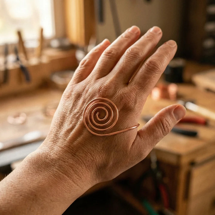 Close-up view of copper spiral hand cuff showing hand-formed wire construction and adjustable tail design